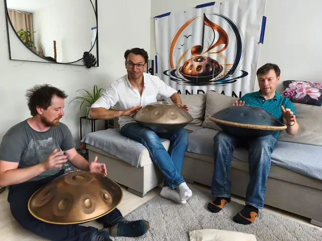 Zdjęcie ze spotkania społeczności Handpan Łódź — trzy osoby grają na handpanach, w tle baner z logo grupy